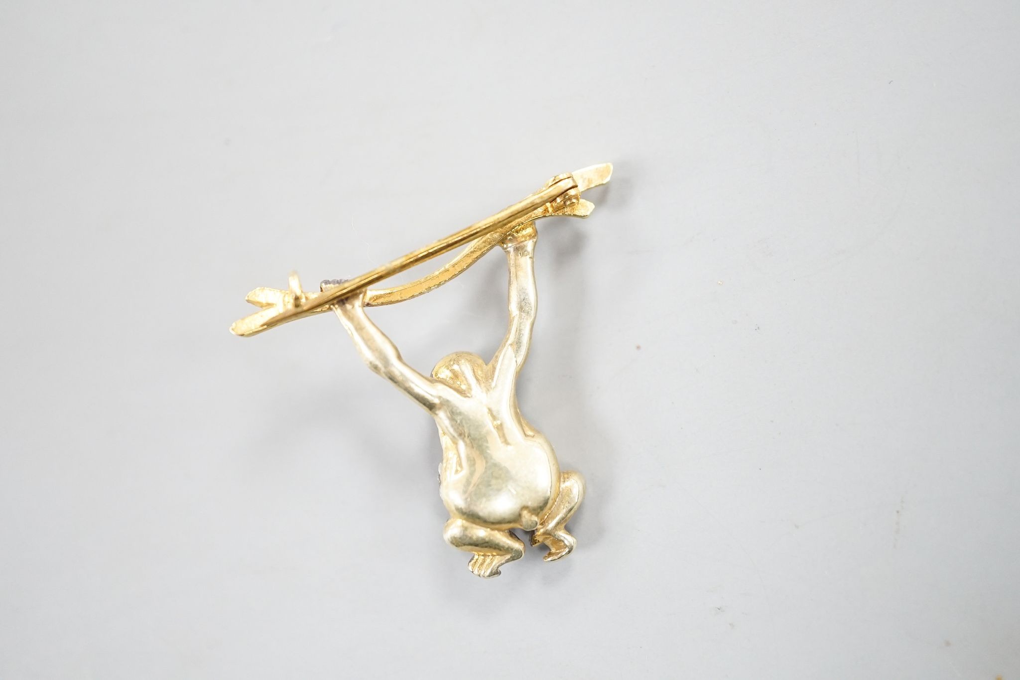 A Victorian style novelty white and yellow metal, diamond chip set brooch, modelled as a monkey hanging from a branch